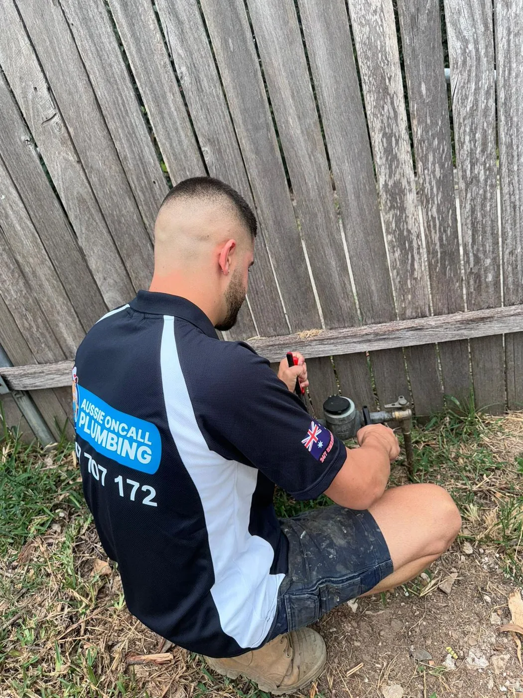 Gas fitter working at an outside meter and fence line